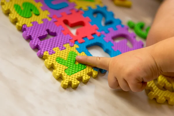 Colorful foam puzzle letters and numbers in kid\'s hands on a light table