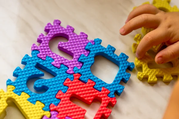 Colorful foam puzzle letters and numbers in kid\'s hands on a light table