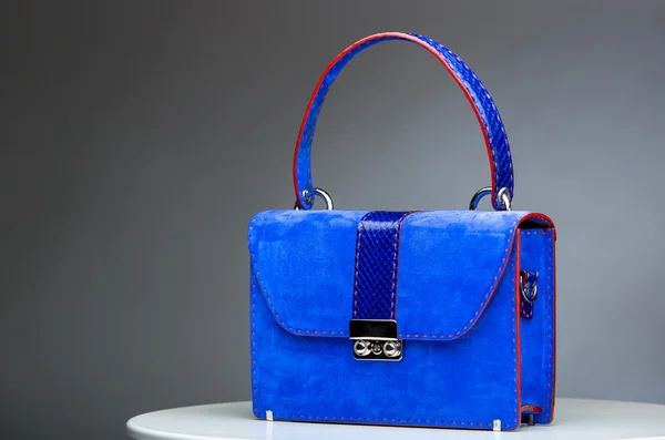 Blue female leather bag with reptile skin details isolated on grey.