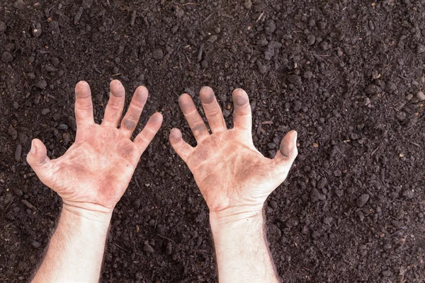 Bare hands with clenched expression over bare soil