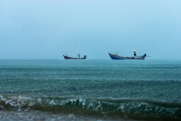 Fishing boat on the sea with raining in the sea.