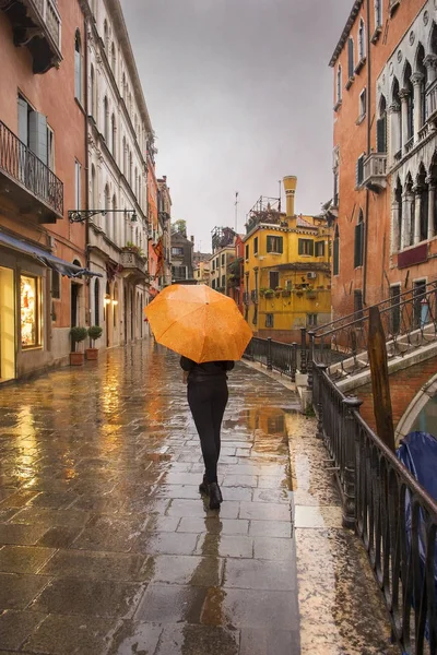Girl with umbrella on promenade of Venice during a rain