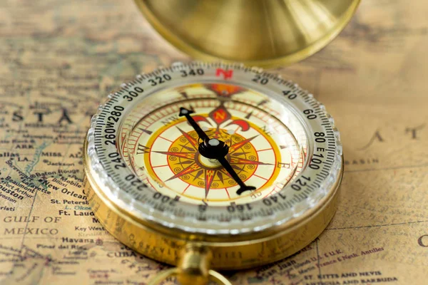 The old gold compass with cover on vintage map, macro background