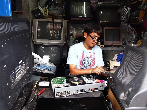 An electrician works on a household appliance inside his repair shop.