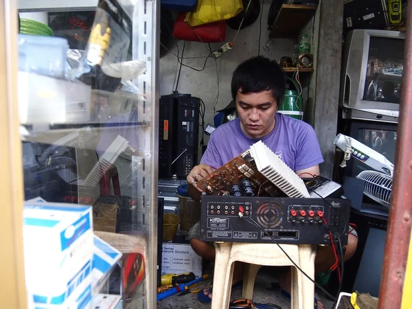 An electrician works on a household appliance inside his repair shop.