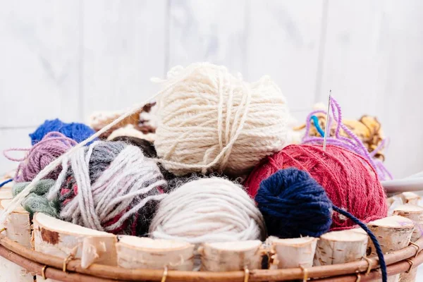 Colorful wool balls and needles in wooden basket