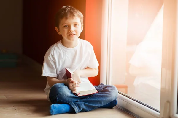 Little 7 years old boy reading a book.