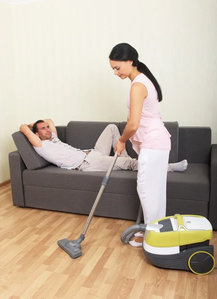 Vacuuming woman and resting man
