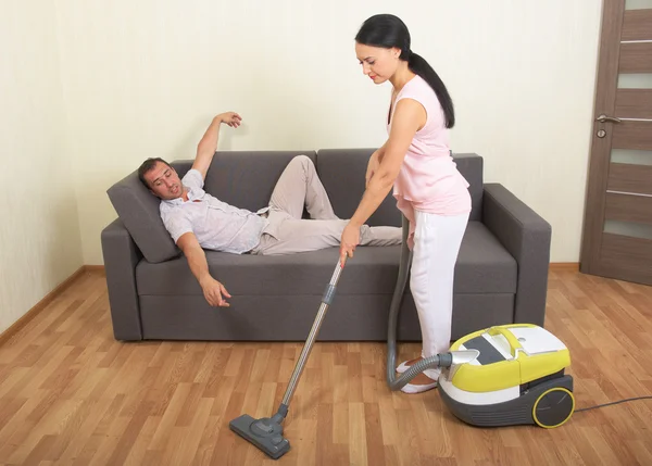 Vacuuming woman and resting man