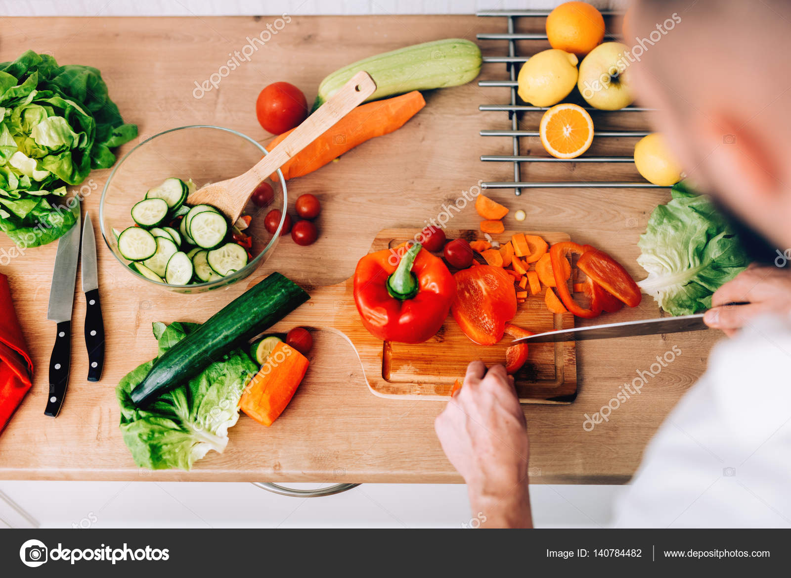 Gut aussehender mann zu hause vorbereiten salat und suppe in modernen küche kochen stockdatei