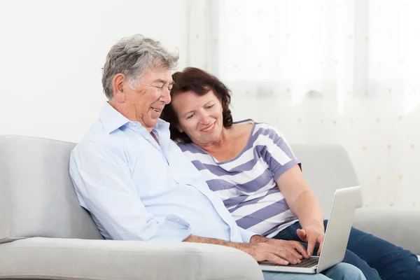 Senior couple laughing while using laptop