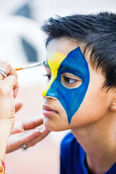 Boy child young having his face painted for fun at a birthday party