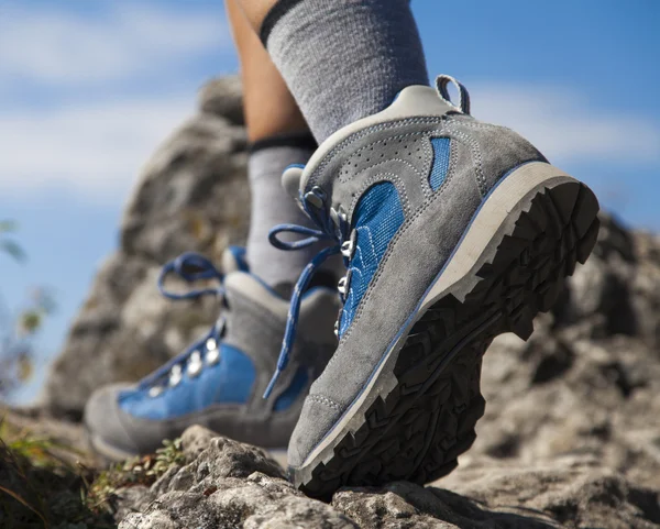 Close up of hiking boots and legs climbing up rocky trail