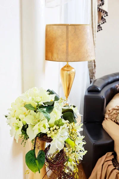 Golden vase with flowers near beautiful table lamp