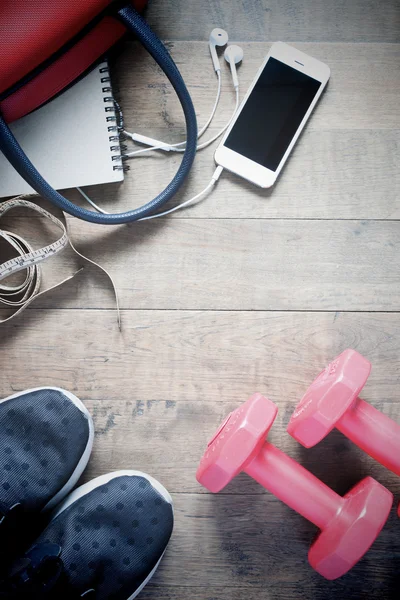 Flat lay of cellphone and sport equipment on wooden background.