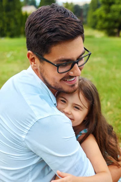 Father And Daughter Hugging In Park. Family Embracing Outdoors