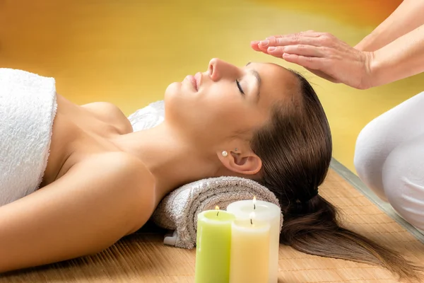 Woman receiving reiki treatment on forehead.