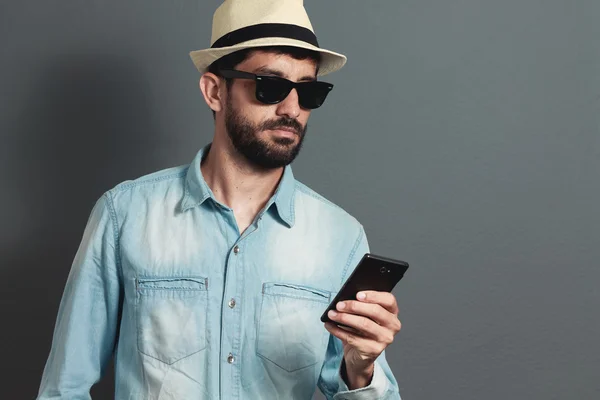 Young hipster bearded man wearing hat - gray background