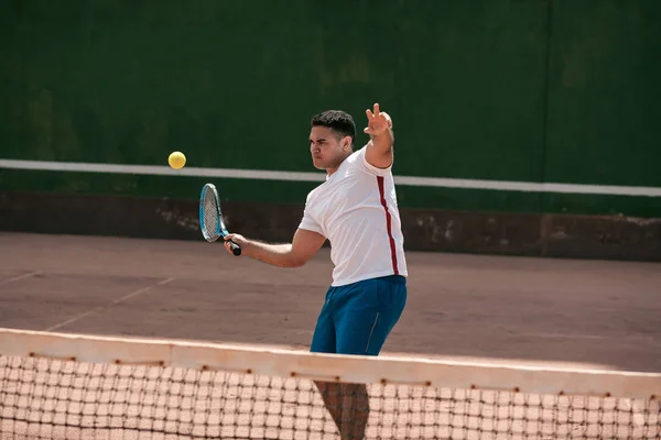 Handsome young man on tennis court. Man playing tennis. Man hitting tennis ball