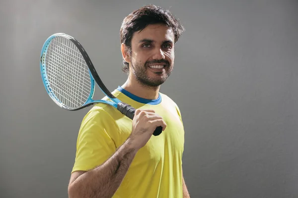 Portrait of young man tennis player with racket over his shoulde