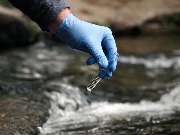 Water sample. Gloved hand into the water collecting tube. Analysis of water purity, environment, ecology - concept. Water testing for infections, harmful emissions