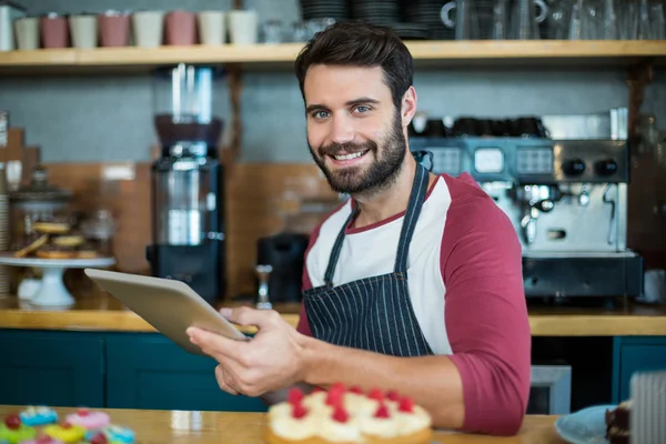 Waiter using digital tablet at counter in cafe