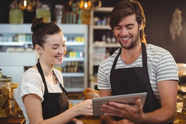 Waiter and waitress using tablet at counter