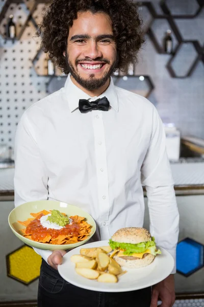 Waiter holding plates of snacks and burger