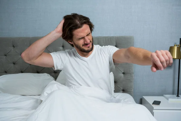 Man waking up in bed and stretching her arms