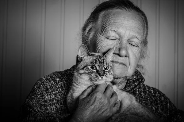 Portrait of an elderly woman with cat on a light background. Ton