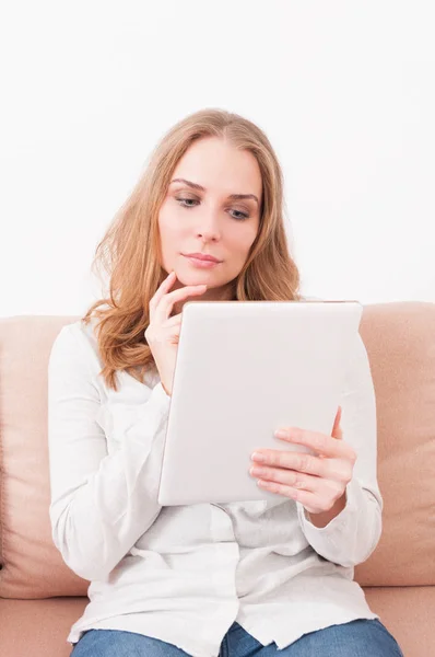 Lady laying on couch being pensive looking on tablet