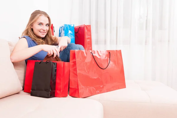 Lady sitting on couch finding things in shopping bags