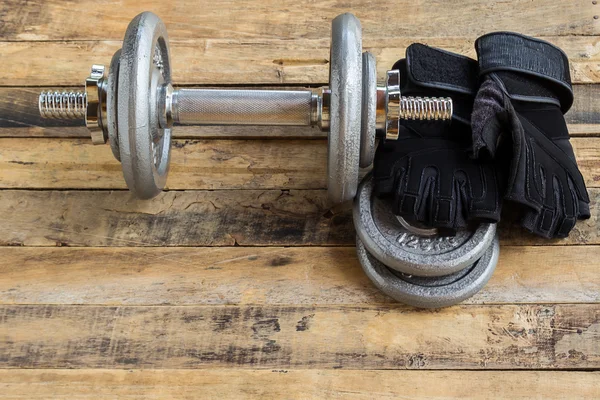 Top view of dumbbells, extra weights and black gloves