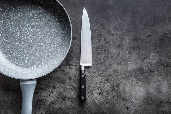 Ceramic pan with knife on concrete kitchen board. Kitchen utensil. Empty pan