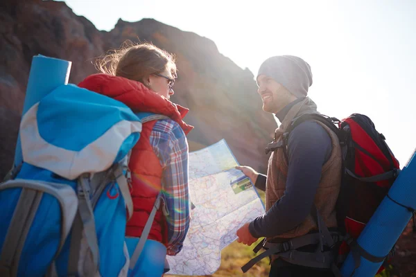 Modern tourists with backpacks using map