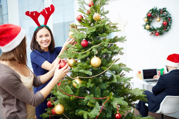 Businesswomen decorating Christmas tree in office