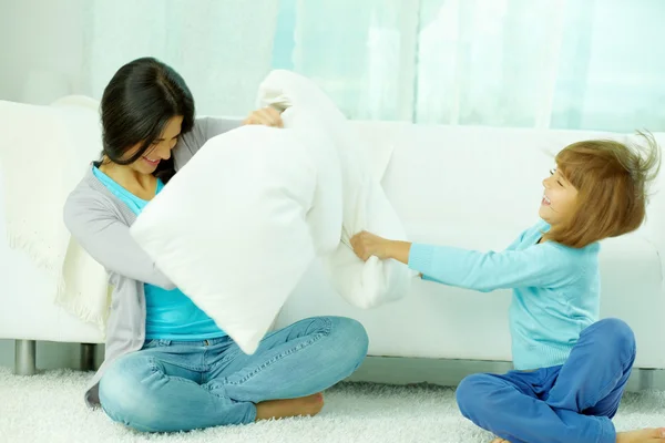 Mother and her daughter fighting with pillows