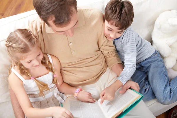 Father with children reading book together