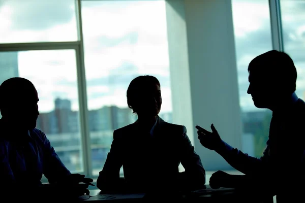 Three businesspeople talking in dark office