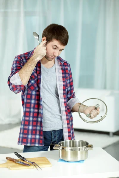 Man looking at saucepan in confuse