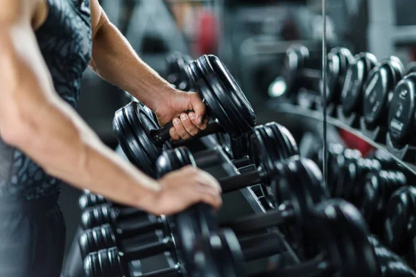 Strong sportsman choosing barbell for workout