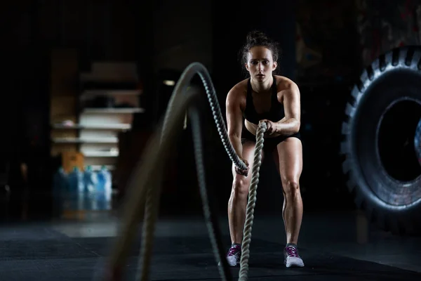 Young woman doing battle rope exercises