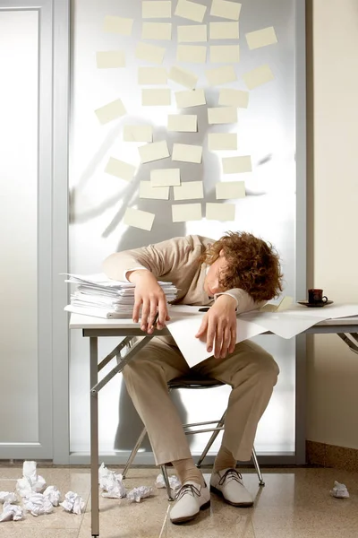Man sleeping on table with pile of papers