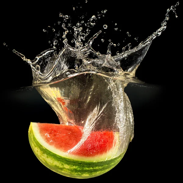 Fresh melon falling in water with splash on black