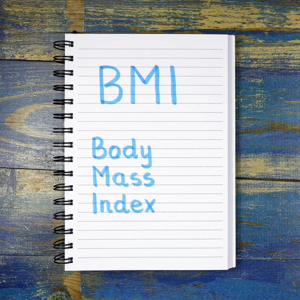 BMI- Body Mass Index acronym written in notebook on wooden background