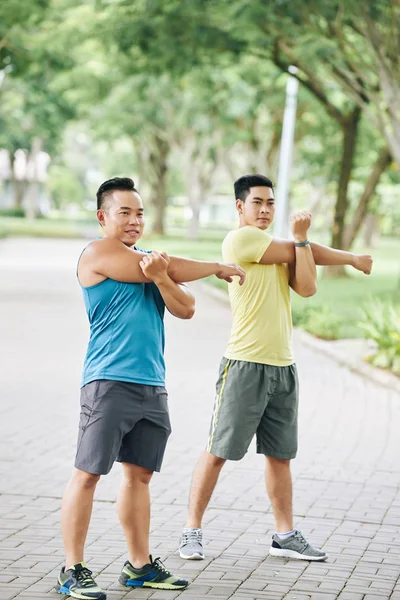 Men stretching arms after jogging