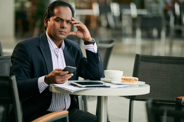 Businessman drinking coffee and checking smartphone