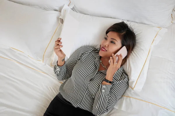 Business lady lying in bed and talking on phone