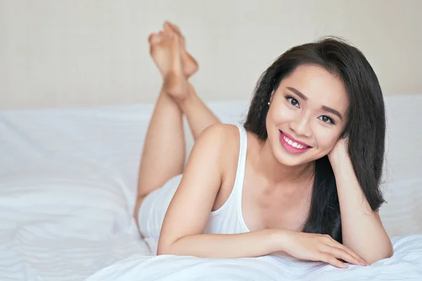 Woman lying in bed and smiling at camera