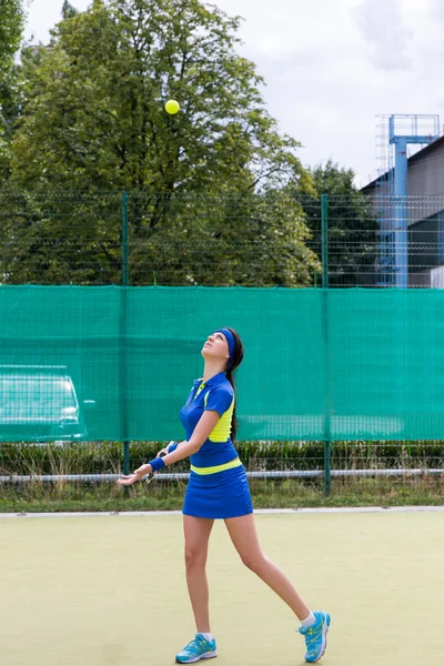 Female tennis player serving during a match